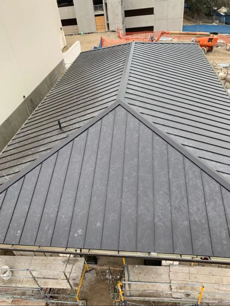 Commercial metal roof construction with crane equipment in Lowell